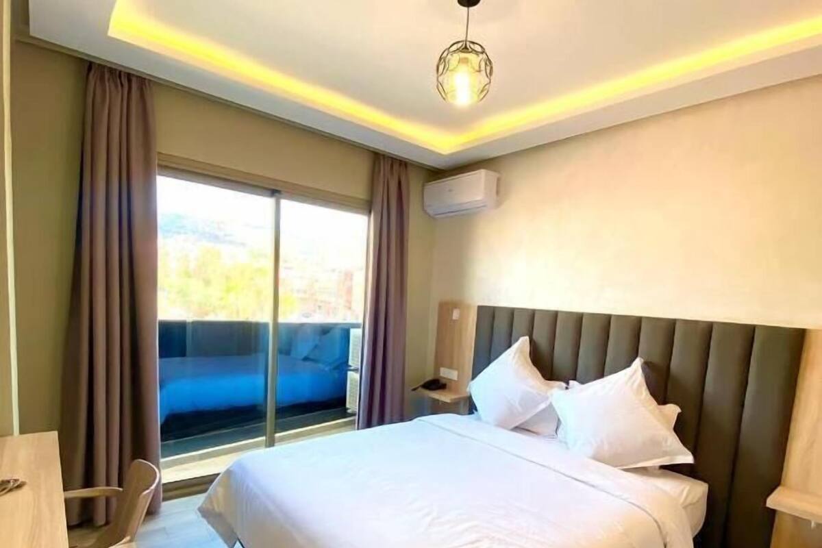 Una habitación de hotel moderna con una cama grande, un escritorio y vistas de la ciudad a través de la ventana.