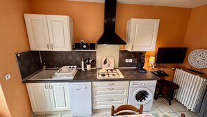 A compact kitchen with white cabinets, a Bosch dishwasher, a gas stove, and a washing machine. - Les Capucines Le Mont Dore 2pers (Mont-Dore)
