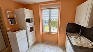 A compact kitchen with white cabinets, a microwave, oven, and a sink. - Les Capucines Le Mont Dore 2pers (Mont-Dore)