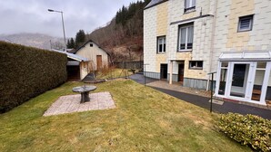 Un quartier résidentiel avec une pelouse bien entretenue, une table en pierre et une maison dont on aperçoit le garage et une fenêtre ornée d’un rideau.