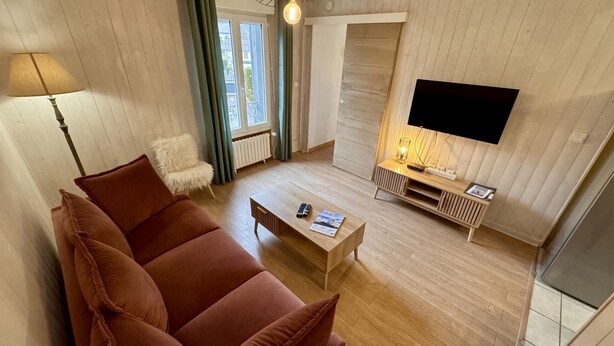 Un salon avec un canapé, une table basse, un meuble pour la télévision et une lampe.