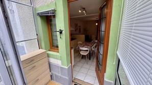 Une cuisine compacte comprenant un coin repas, un meuble en bois et une fenêtre avec des stores.