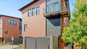 Un edificio moderno de dos pisos con techo plano, ventanas grandes y un balcón.