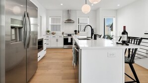 Una cocina moderna con electrodomésticos de acero inoxidable, una isla central e iluminación colgante.