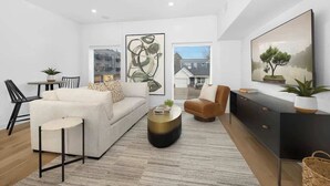 Ein modernes Wohnzimmer mit Sofa, Sessel, Couchtisch und Kunstwerken an den Wänden.