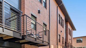 Un bâtiment moderne avec des façades en briques, de grandes fenêtres et un trottoir dallé.