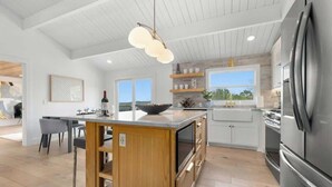Une cuisine moderne dotée d’un îlot central, de meubles en bois et d’un réfrigérateur en acier inoxydable.