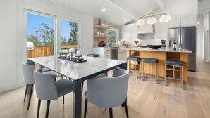Une cuisine moderne avec un plan de travail en marbre, des chaises grises et un îlot central doté de tabourets.