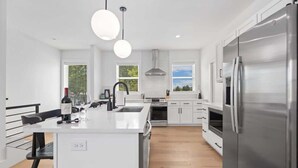 A modern kitchen with stainless steel appliances, a central island, and pendant lighting.