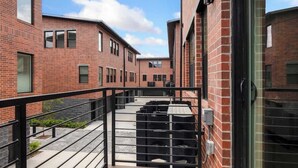 A modern building with brick exterior walls and a metal balcony railing.