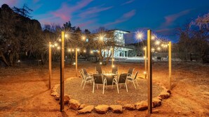 Un espace de restauration en plein air, avec une table et des chaises, entouré de rochers et illuminé de guirlandes lumineuses.