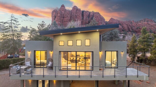 A modern two-story house with a balcony, large windows, and a view of red rock formations. - Moondance Red Rock Retreat | Views |Private Studio (Sedona)