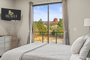 A hotel room with a bed, a flat-screen TV mounted on the wall, a view of a red rock formation, and a balcony with a railing. - NEW|Moondance Red Rock Retreat|Epic Views (Sedona)