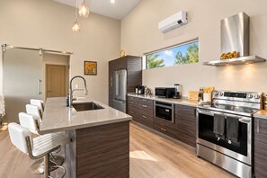 A modern kitchen with a central island, stainless steel appliances, and a large window.