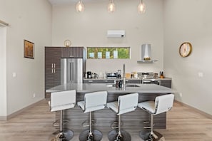 A modern kitchen with a central island, bar stools, stainless steel appliances, and pendant lighting. - NEW|Moondance Red Rock Retreat|Epic Views (Sedona)