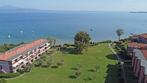 A hotel with a red-tiled roof, multiple balconies, and a view of the sea. - Specchio sul Lago (Manerba del Garda)