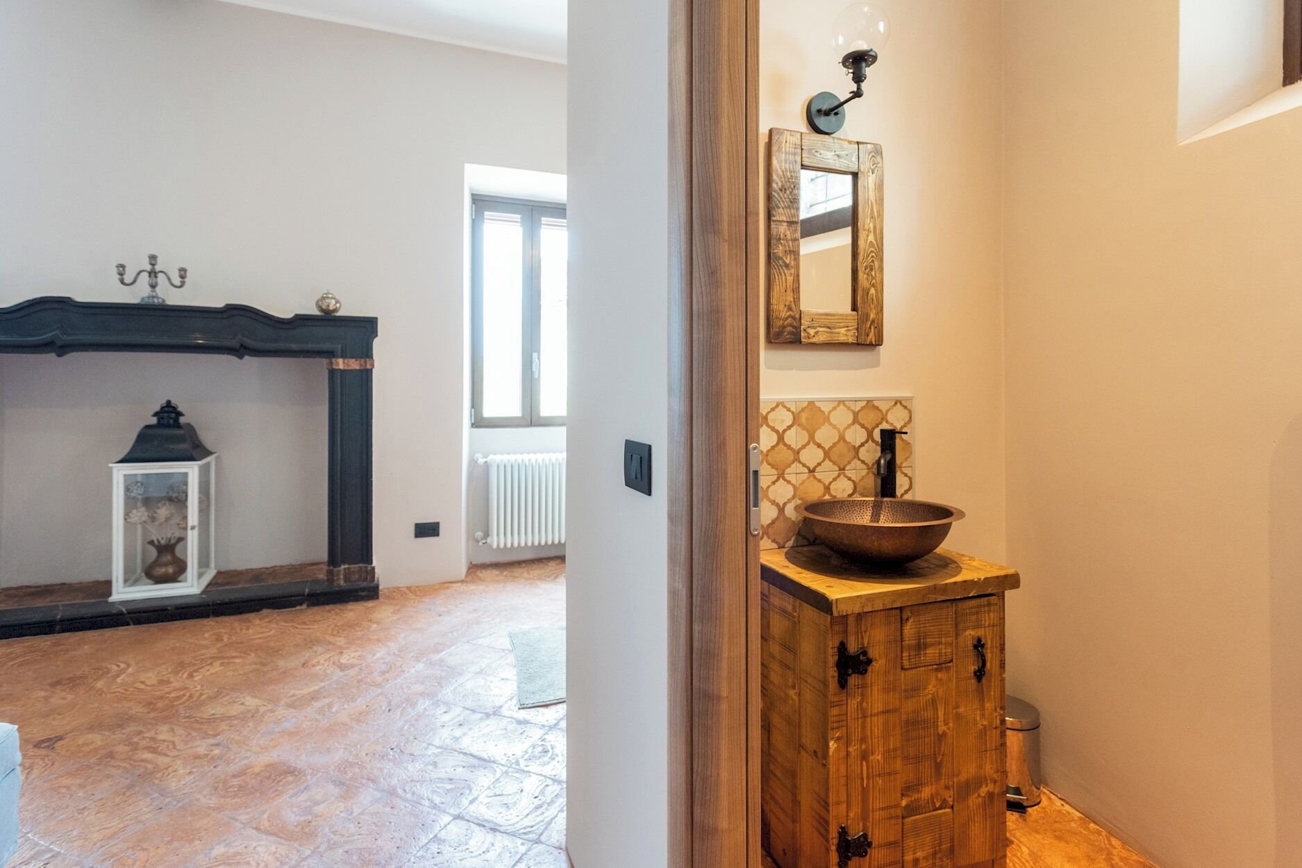 Ein Flur mit einem Holzschrank, einem Spiegel und einem rustikalen Waschbecken.