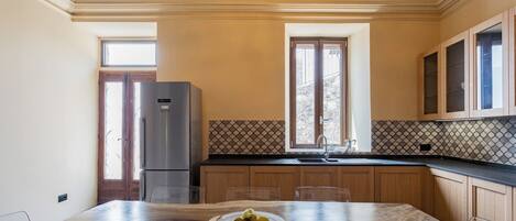 A kitchen with a wooden table, a refrigerator, and a window with a view.