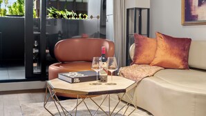 Un salón moderno con un sofá de cuero, una mesa de vidrio con un libro y vasos, y una botella de vino.