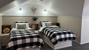 Een slaapkamer met twee bedden, een houten hoofdbord, een aan de muur bevestigd hertenhoofd en een kleine plant.