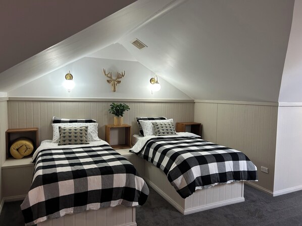 A bedroom with two beds, a wooden headboard, a wall-mounted deer head, and a small plant. - 3 bedroom home, Located on the main street of Crookwell (Crookwell)