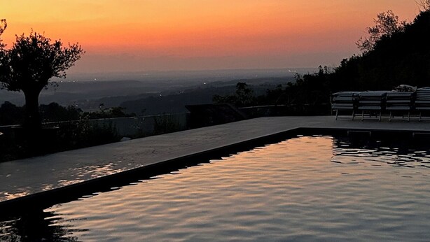 A serene sunset view over a calm pool with a tree silhouette and distant cityscape. - Gavi - Renovated, beautiful former winery with great views! (Gavi)