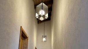 A hallway with wooden doors, a hanging light fixture, and a view into another room. - Gavi - Renovated, beautiful former winery with great views! (Gavi)
