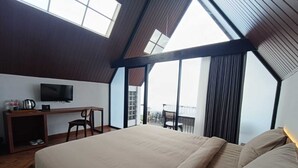 Un dormitorio con una cama grande, un escritorio, una televisión y un balcón con vistas.