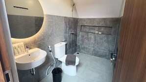 Un baño moderno con espejo redondo, lavabo blanco, inodoro y ducha.