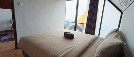 A bedroom with a large bed, a view of the outside, and a balcony.