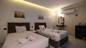 Ein Hotelzimmer mit zwei Betten, einem Schreibtisch und einem Spiegel.