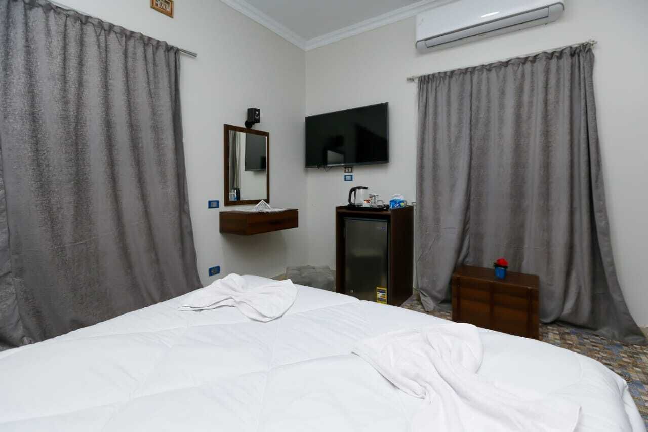 A hotel room with a bed, a TV, a small desk, and a mirror.