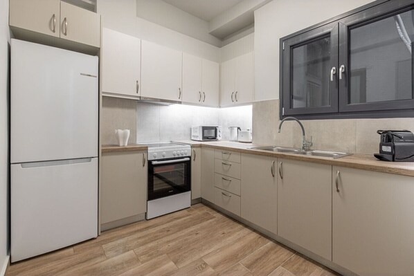 A kitchen with white cabinets, a built-in oven, a microwave, and a coffee machine.