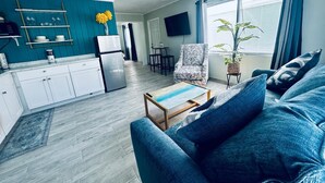 A modern living room with a blue sofa, a coffee table, and a TV mounted on the wall. - Experience the passion of hospitality, cleaning, and good location! (Bradenton Beach)