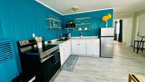 A kitchen with teal walls, white cabinets, a black stove, and a white refrigerator. - Experience the passion of hospitality, cleaning, and good location! (Bradenton Beach)