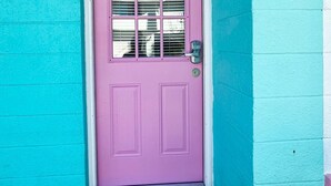 A turquoise building with a pink door, numbered 203, and a doormat with the word "welcome". - Experience the passion of hospitality, cleaning, and good location! (Bradenton Beach)