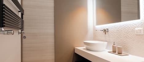A modern bathroom with a white sink, a large mirror, and two pendant lights.