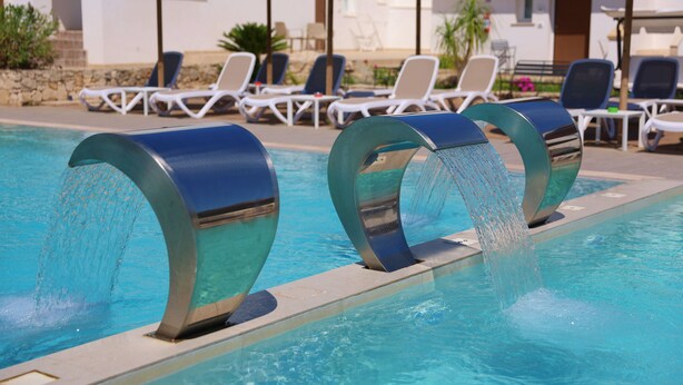 A pool with two water features and lounge chairs in the background. - Grotta Saracena (Porto Cesareo)