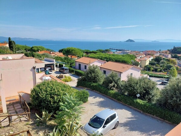 Zona residencial con casas, un coche y vistas al mar.