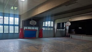 An indoor basketball court with two hoops, padded walls, and a large open space.