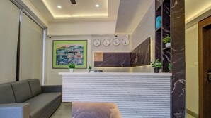 Una moderna zona de recepción con un mostrador blanco, un sofá gris y una mesa de centro con estampado de mármol.