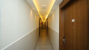 Pasillo de hotel con una puerta de madera con la etiqueta '102' y un interior moderno y bien iluminado.