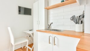 A compact kitchen with white cabinetry, a wooden countertop, a built-in sink, and a small table with a chair. - Studio with panoramic view of the Eiffel Tower (Paris)