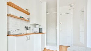 A modern kitchen with white cabinets, wooden countertops, and a built-in microwave. - Studio with panoramic view of the Eiffel Tower (Paris)