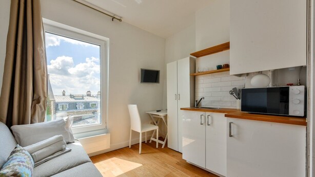A modern apartment with a kitchenette, a dining area, and a sofa. - Studio with panoramic view of the Eiffel Tower (Paris)
