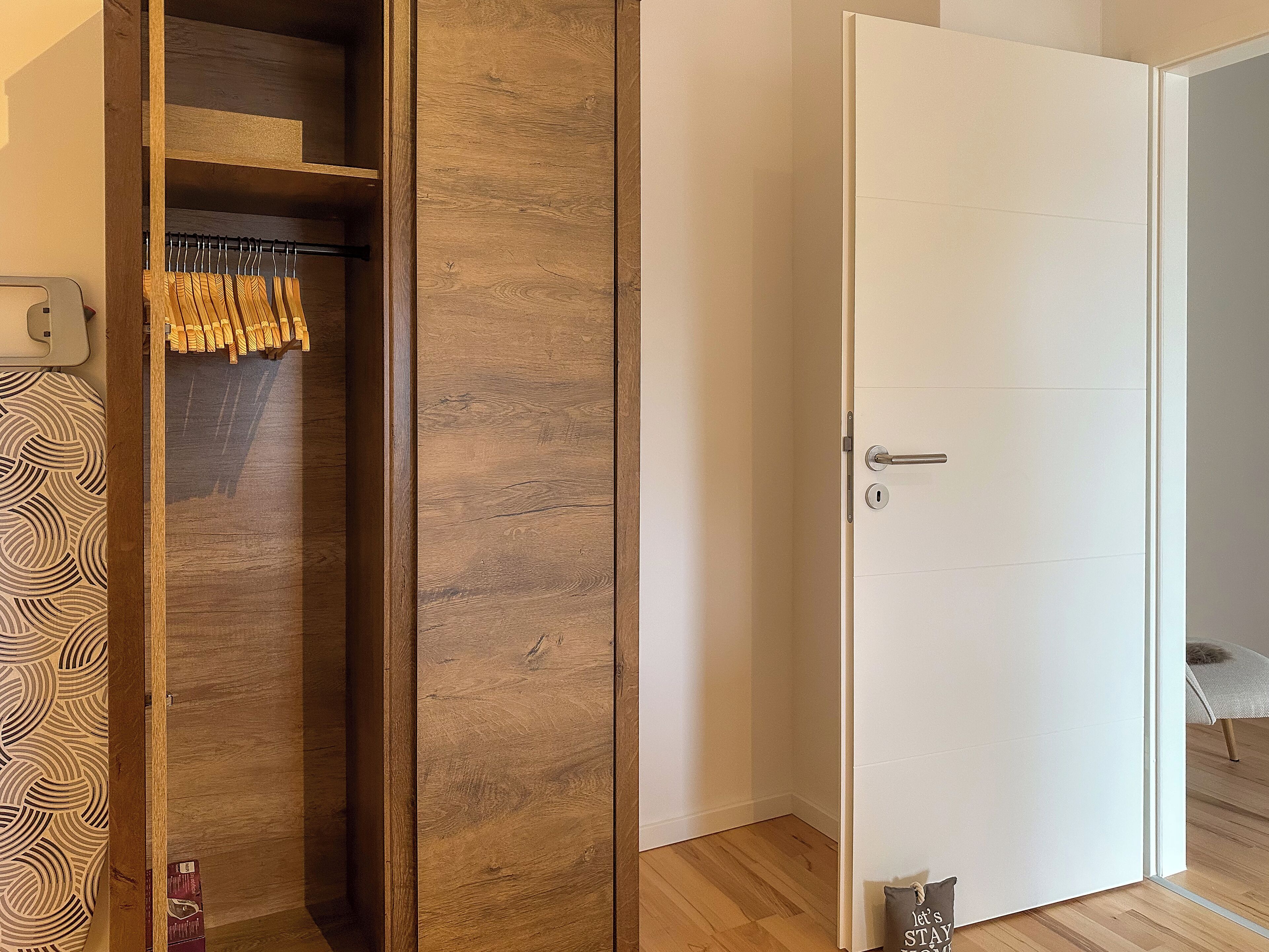 Ein Zimmer mit einem Holzschrank, einer weißen Tür und einer Wand mit Muster.