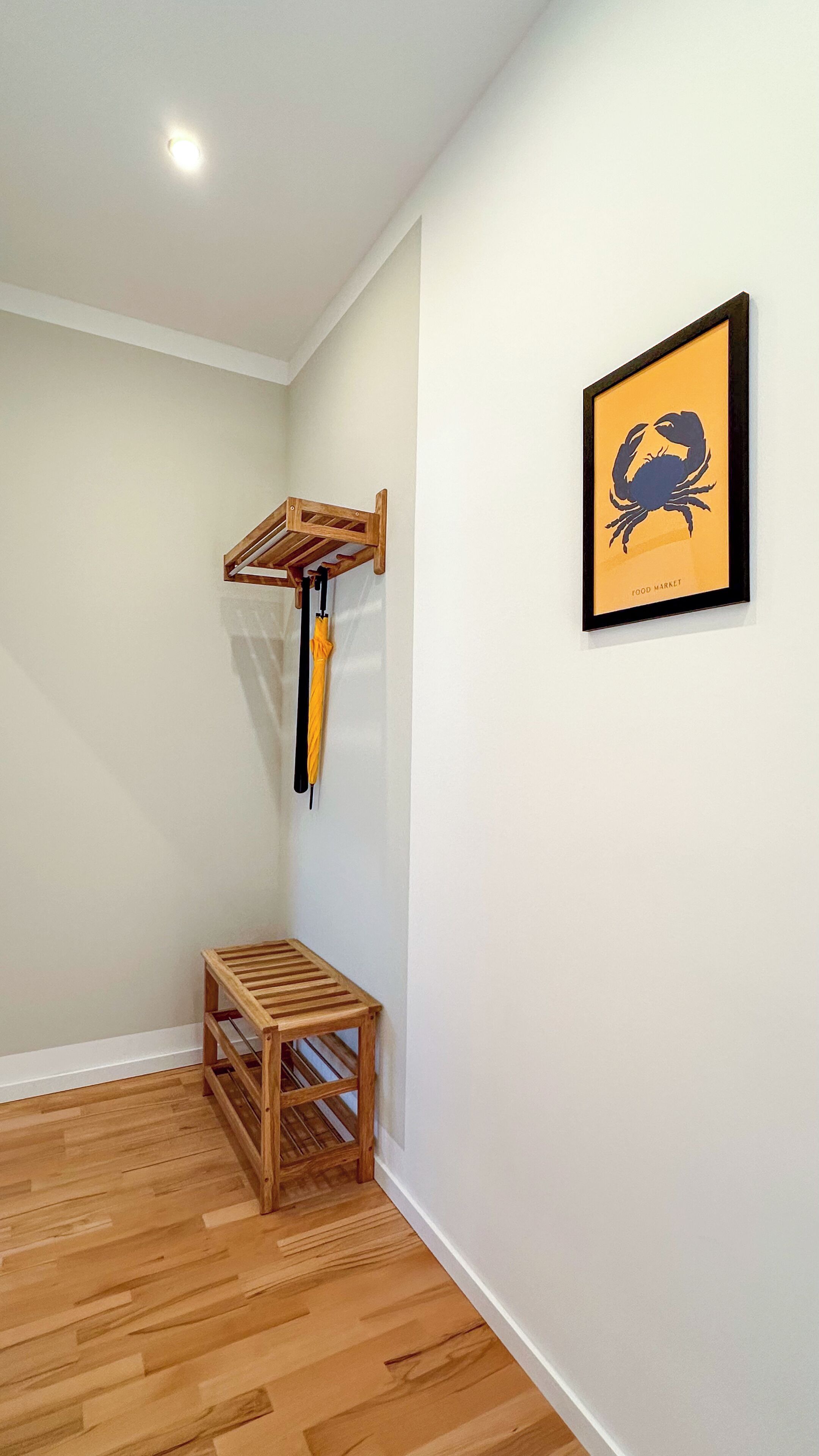 A room with a wooden bench, a hanging rack, and a framed picture on the wall.