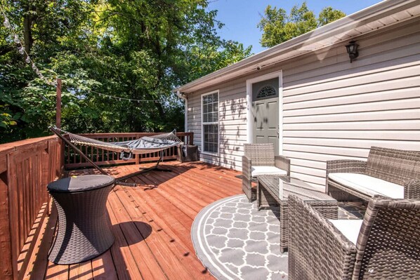 A wooden deck with a hammock, wicker furniture, and a patterned rug. - Family Retreat in Birmingham – 7BR/4BA (Birmingham)
