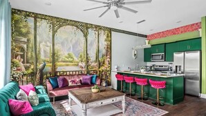 A living room with a green sofa, a coffee table, and a large window with a view of a garden.