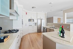 A modern kitchen with white cabinetry, stainless steel appliances, a gas stove, and a dishwasher.